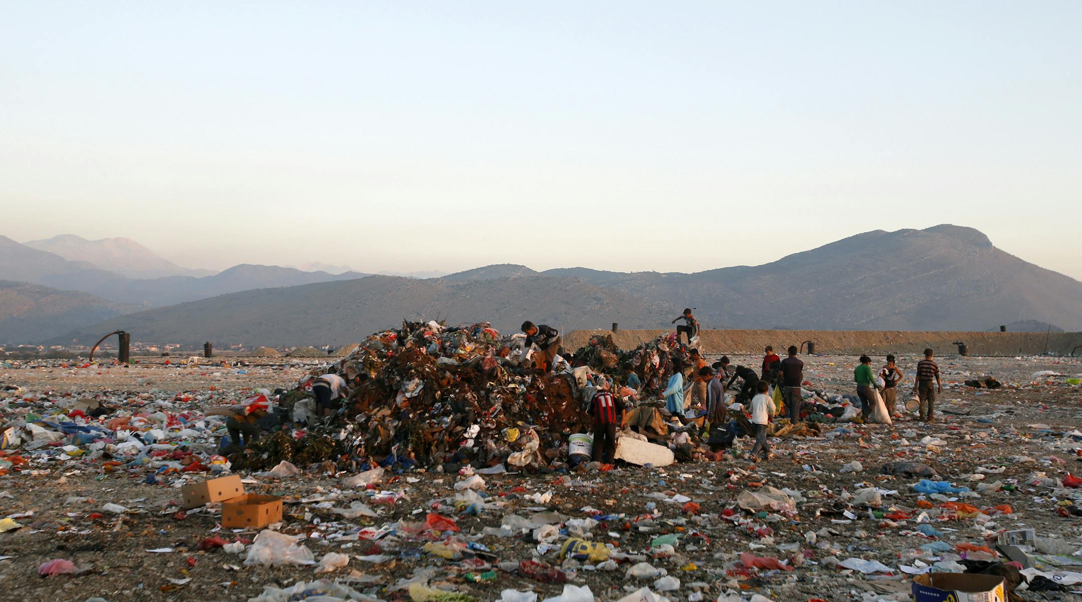 In this photo taken Monday, Nov. 3, 2014, people collect plastic bottles and cans at waste dump in Podgorica, Montenegro. Montenegro takes pride in its majestic Adriatic coastline and towering mountains rising from the sea, lined with rivers, streams and lakes. But the so-called Balkan Wild Beauty also faces an ugly problem of waste disposal that is threatening both its natural wonders and lucrative tourism industry. (AP Photo/Darko Vojinovic)