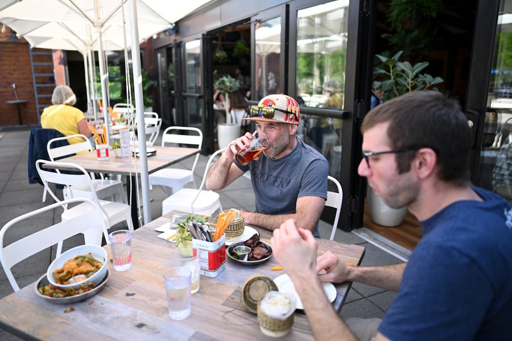 Paul Gonzalez, of Vancouver Island, B.C., and coworker Nick Christman, of Lexington, Kentucky, eat an early dinner on the rooftop patio at Gai Noi  in Minneapolis.