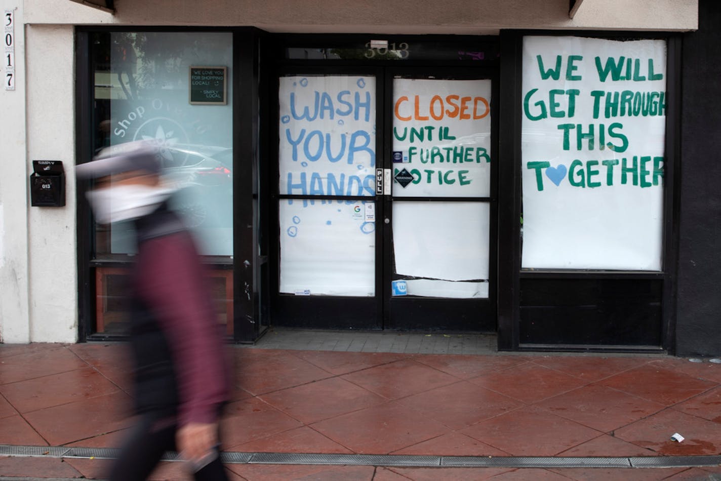 A man passes a store that closed as part of efforts to combat the spread of the new coronavirus. About one in 10 U.S. workers lost jobs in the past three weeks as the country struggles with fallout from the coronavirus pandemic.