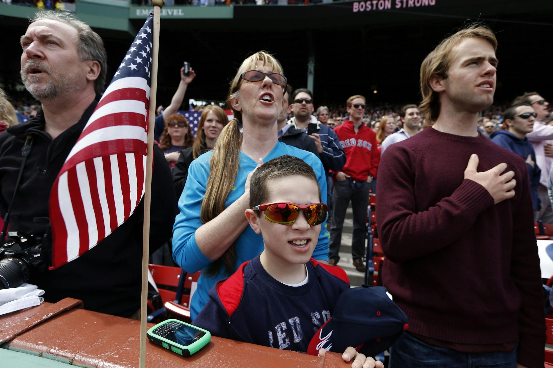 Fans, accompanied by the stadium organist, sing the national anthem before a baseball game between the Boston Red Sox and the Kansas City Royals in Boston.