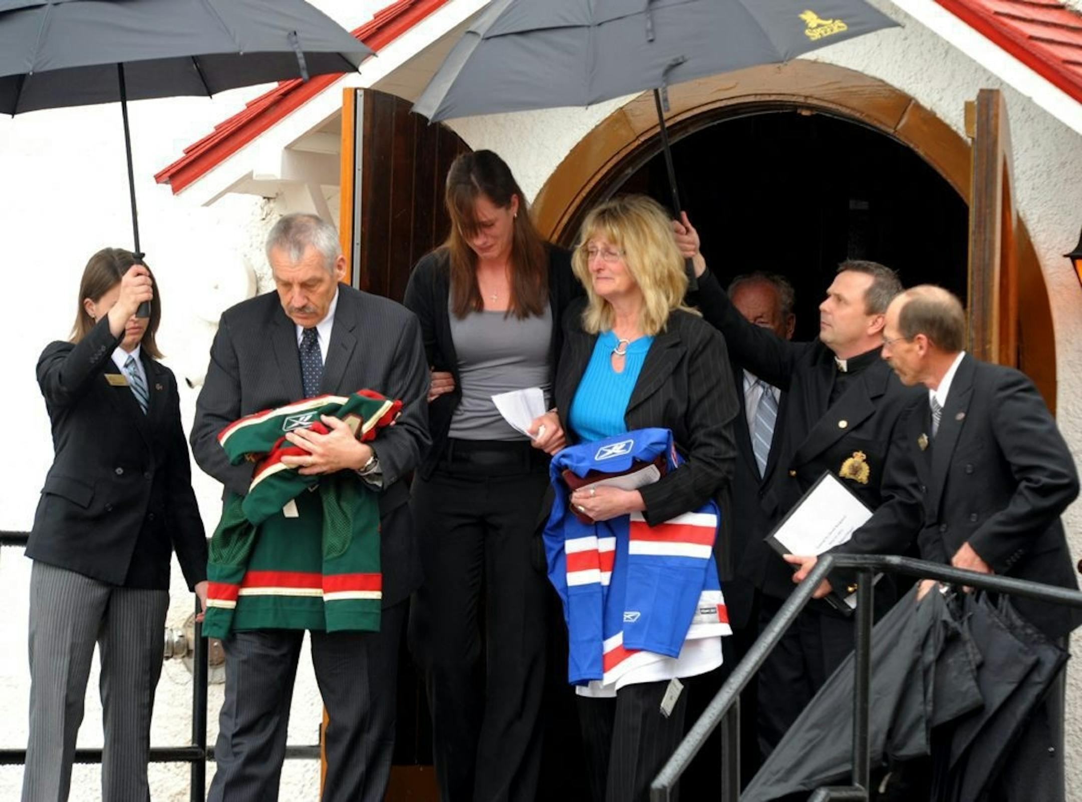 Derek Boogaard's father, Len, holding a Wild jersey; sister Krysten, center, and mother, Joanne, holding a New York Rangers jersey, left Derek Boogaard's funeral in Regina, Saskatchewan, on Saturday.