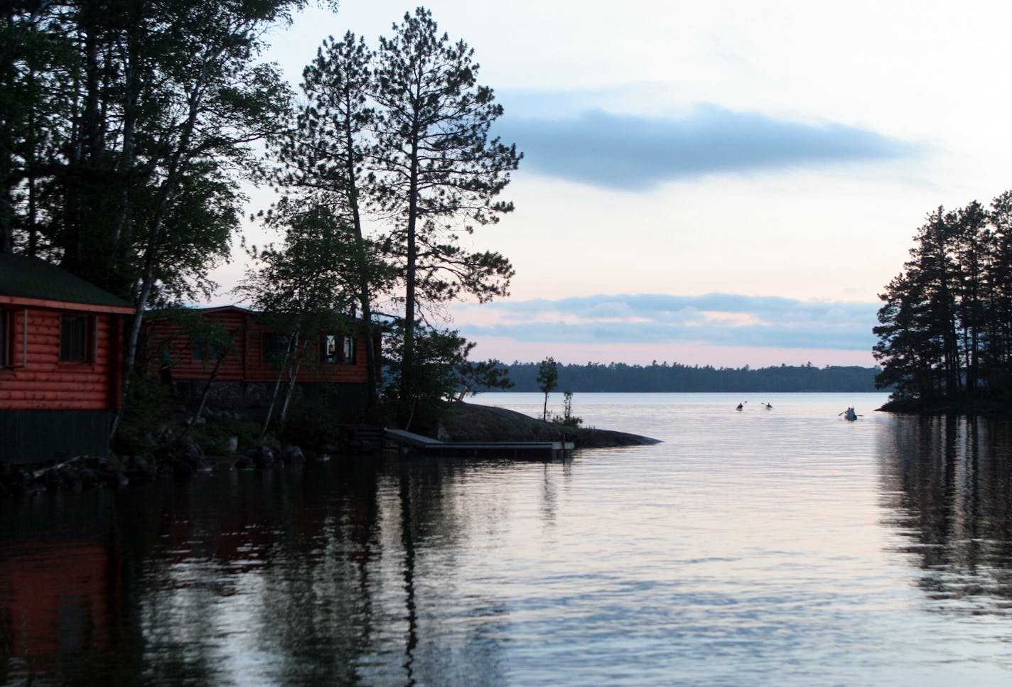 Paddlers maneuver canoes at dusk in the waters off Burntside Lodge.