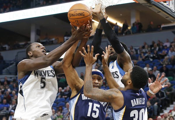 Minnesota Timberwolves' Gorgui Dieng, left, of Senegal, battles Memphis Grizzlies' Vince Carter and Troy Daniels, right, for the rebound during the fi