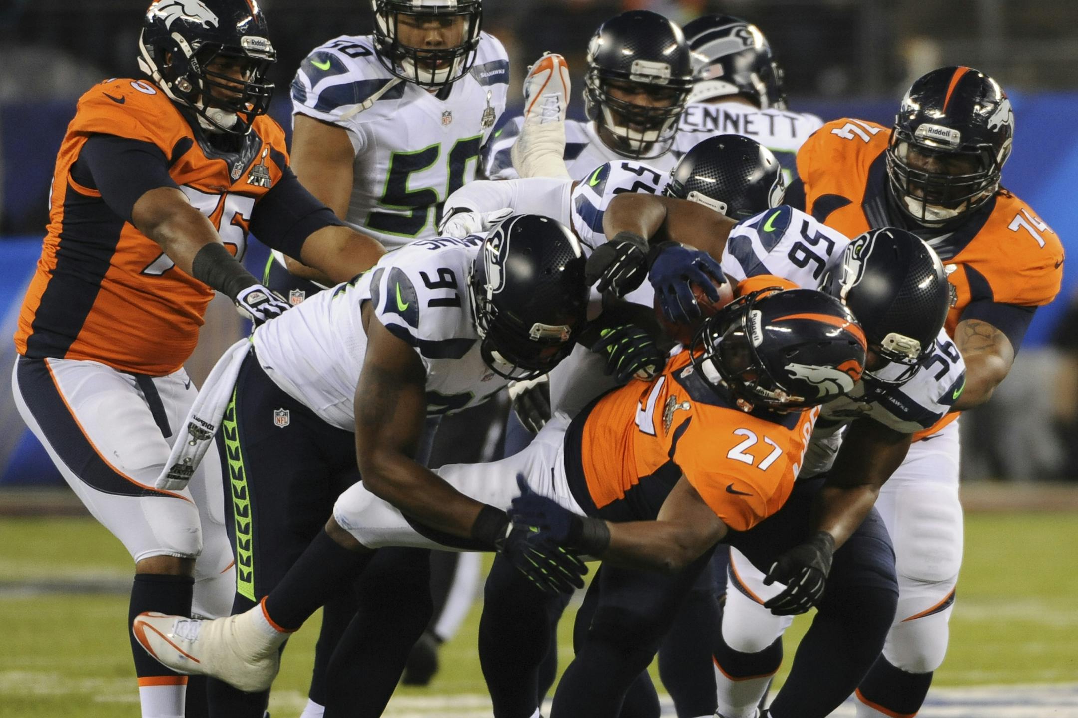 Seattle Seahawks defensive end Chris Clemons (91) and defensive end Cliff Avril (56) tackle Denver Broncos running back Knowshon Moreno (27) in the first half of the NFL Super Bowl XLVIII football game against the Seattle Seahawks at MetLife Stadium in East Rutherford, N.J., Feb. 2, 2014. (Barton Silverman/The New York Times)