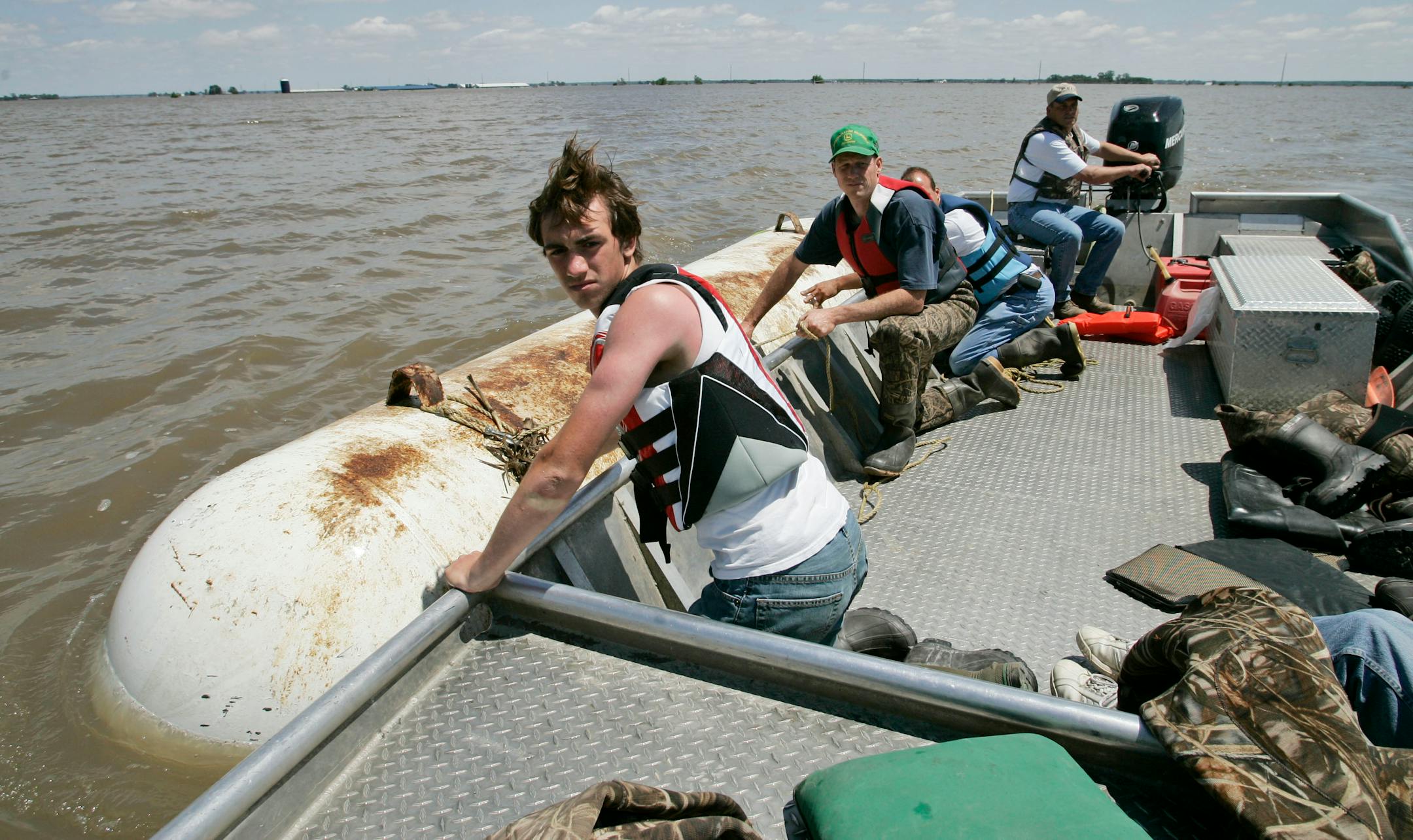 From left: Logan Lanz, Troy Massner, Dave Lanz and Jerry Edle recovered a propane tank from a flooded cornfield Monday in Oakville.