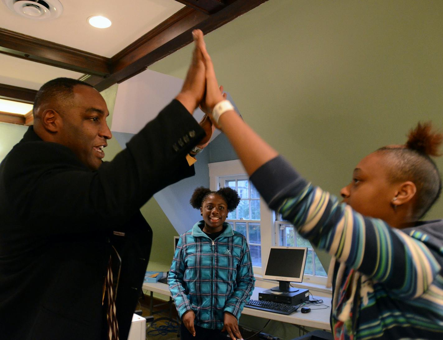 (Left to right) Darrell Thompson, president of Bolder Options, shares a high ten with 12-year-old Jahniesha Hill as 12-year-old Ja'kayla Ellis watches and smiles (at center). They had just finished a game of foosball. Bolder Options teaches youth to succeed. ] Joey McLeister,Special to the Star Tribune,Minneapolis,MN October19,2013