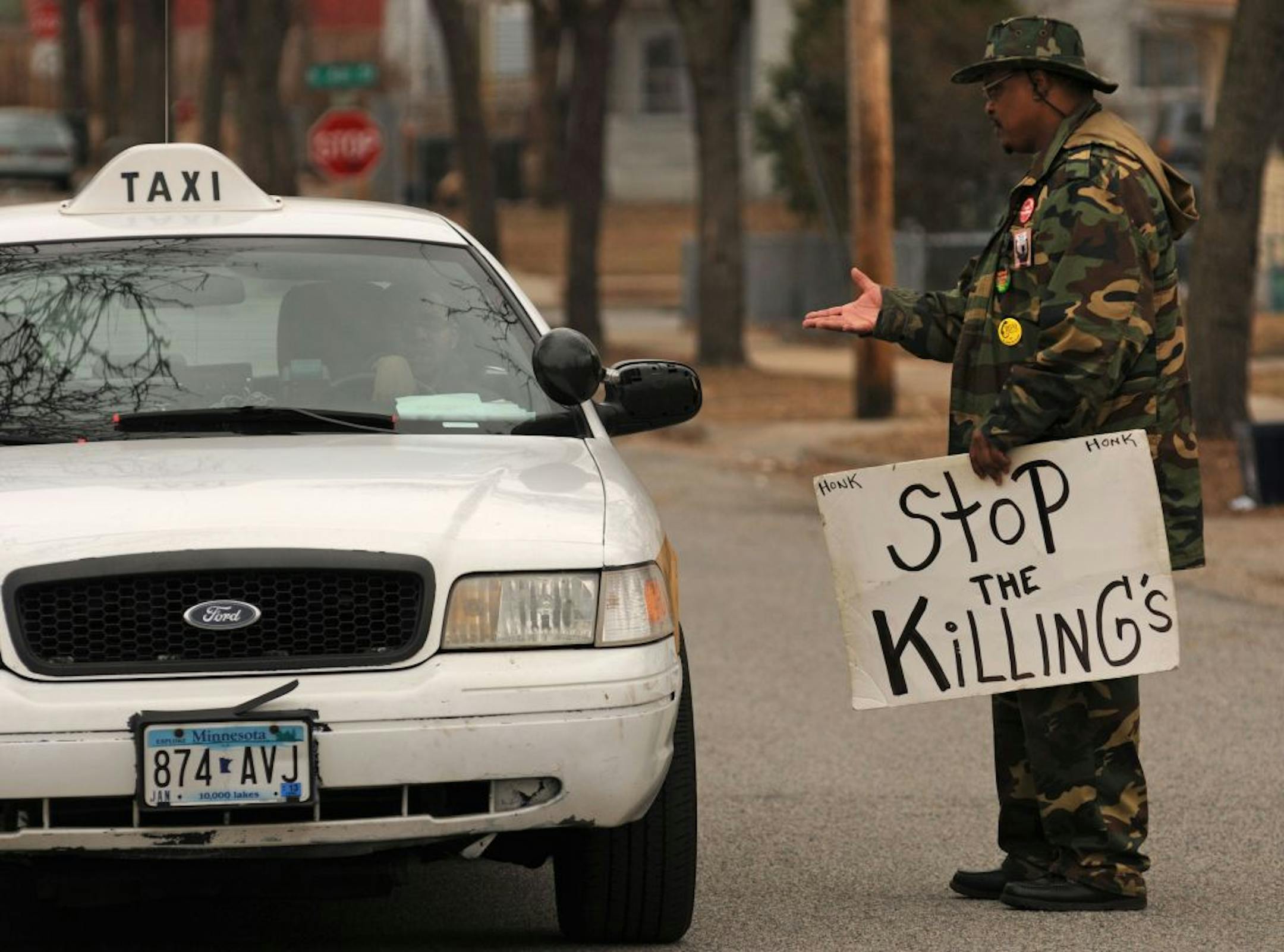 KG Wilson of Hope Ministries stands on 23rd Ave N. holding a sign that reads " Stop The Killing's " while talking to a cabbie that was checking out the scene. He was a few paces from where a cab driver was shot and and later died at North Memorial Hospital. The shooting occurred shortly after 10 p.m. Wednesday near 400 23rd Avenue N., according to police.