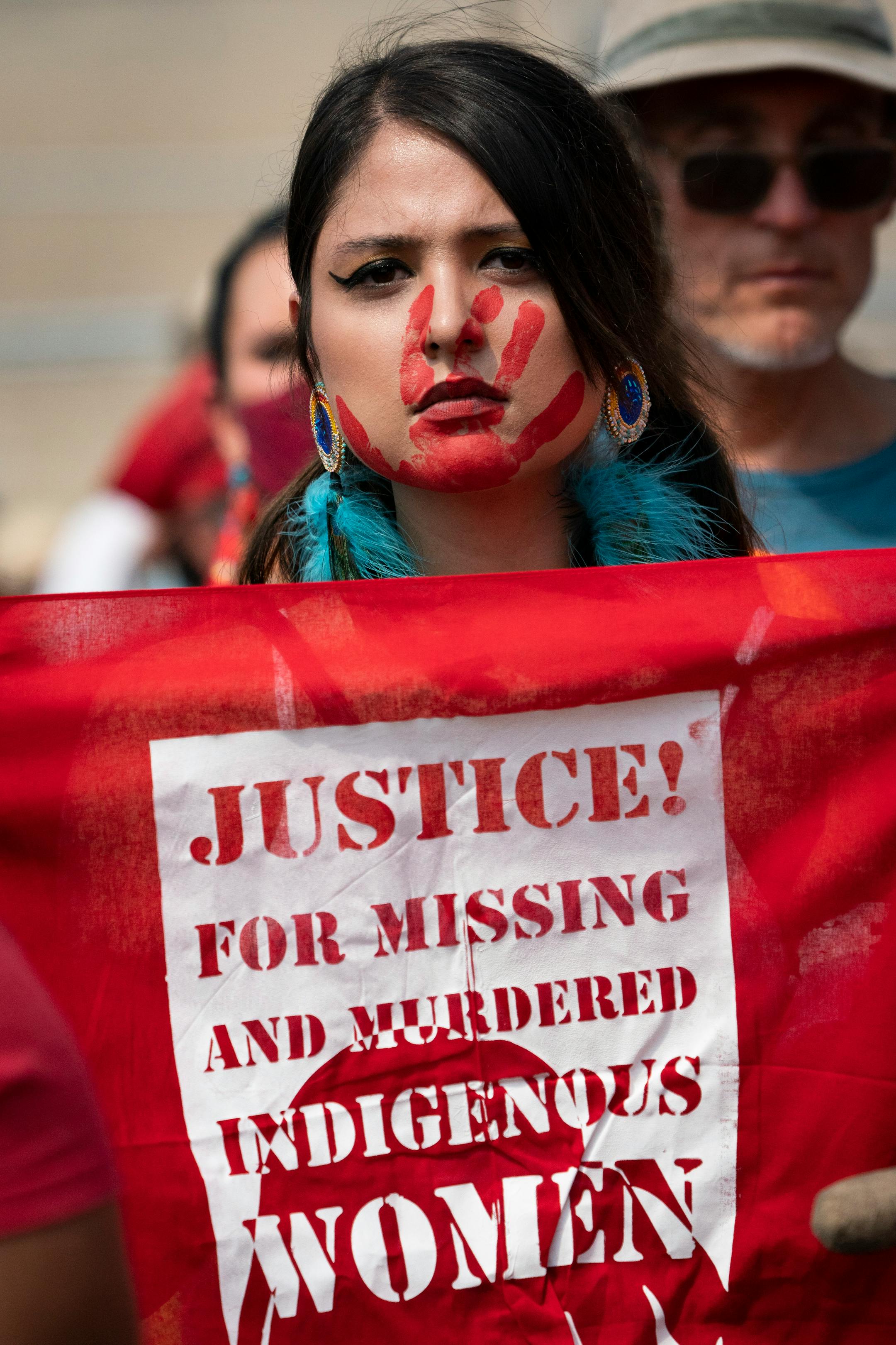 A woman with paint on her face held a sign reading 'Justice for missing and murdered indigenous women,' during a protest against Line 3 and other pipeline projects at the State Capitol in St. Paul, Minn., on Wednesday, August 25, 2021.