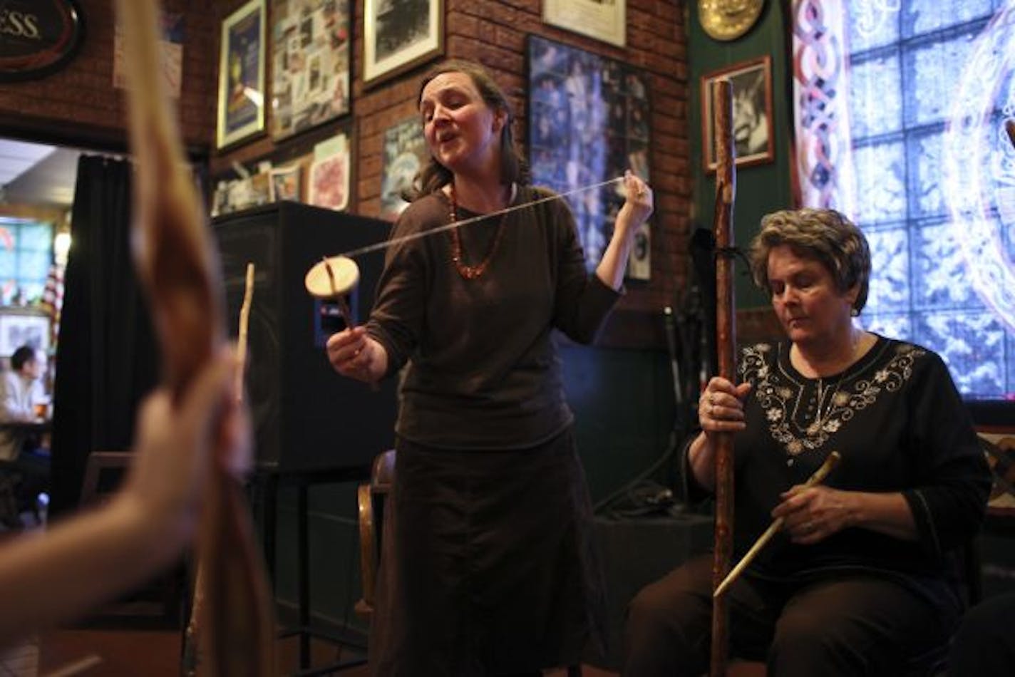 Kari Tauring spun wool and chanted while others, including Neva Banei, right, played wooden stick instruments on a Tuesday night at Merlins Rest Pub.