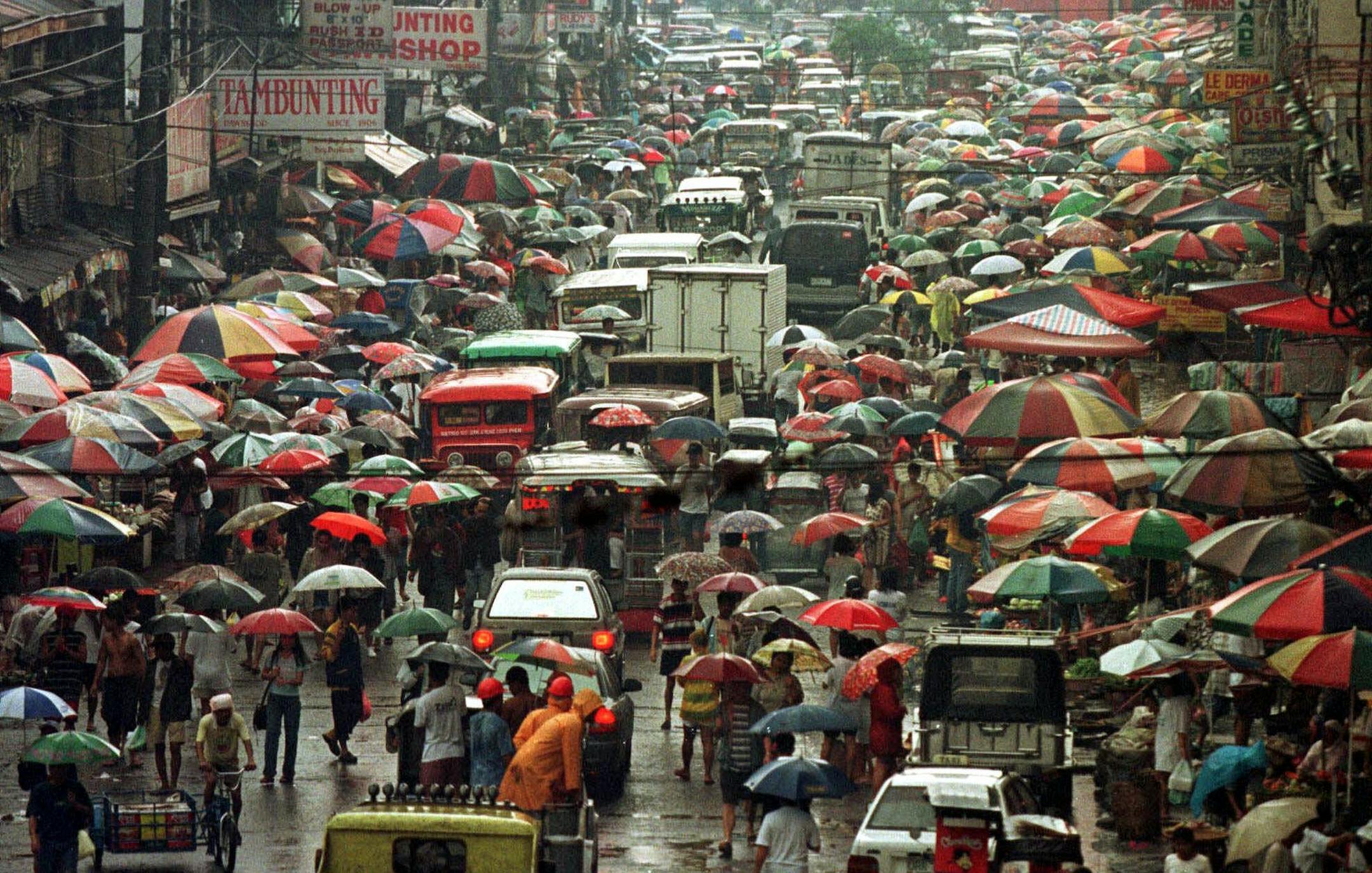 ADVANCE FOR SUNDAY, JAN. 14--FILE--A sea of umbrellas protecting vegetable stalls and shoppers from rain slows the flow of traffic along a street in northern Manila, in this Aug.19, 1997, file photo. The average speed of traffic in Manila on dry days is 7 mph. (AP Photo/Bullit Marquez)