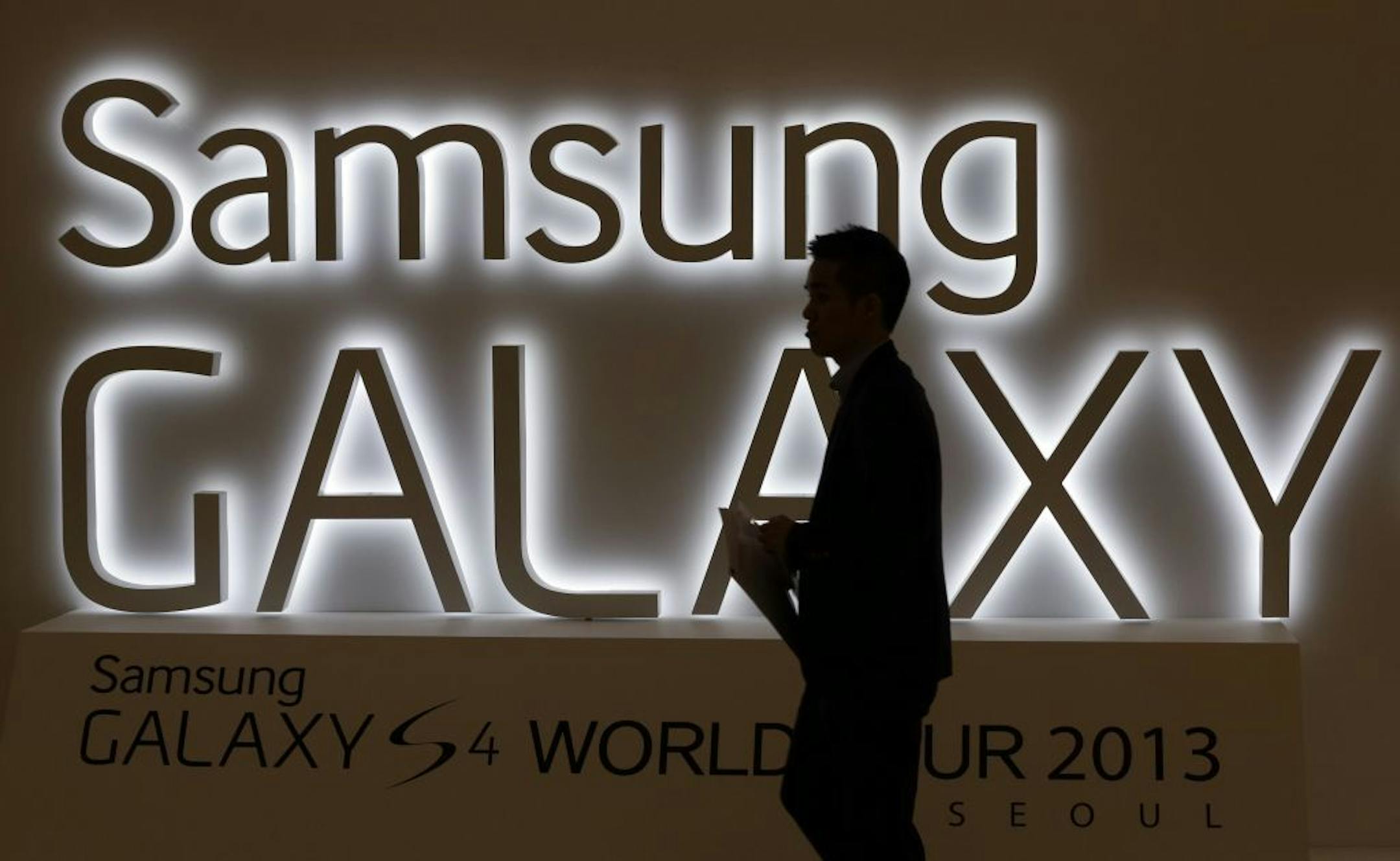 In this photo taken on April 25, 2013, a man walks by a logo of Samsung Electronics Co.'s latest smartphone Galaxy S4 during its unveiling ceremony in Seoul, South Korea. Samsung Electronics Co. has applied for U.S. and South Korean trademarks for a watch that connects to the Internet in the latest sign that consumer technology companies see wearable devices as the future of their business.