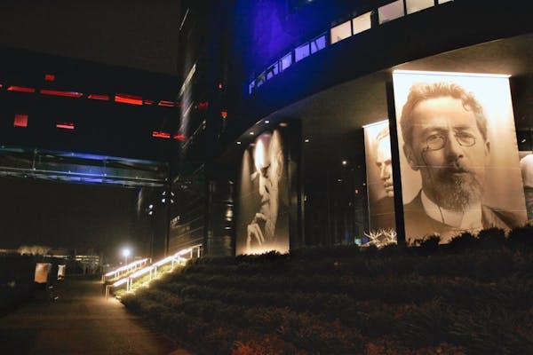 Photos of playwrights, from left, George Bernard Shaw, Eugene O'Neill and Anton Chekhov grace the facade in a night view of the new Guthrie Theater fr