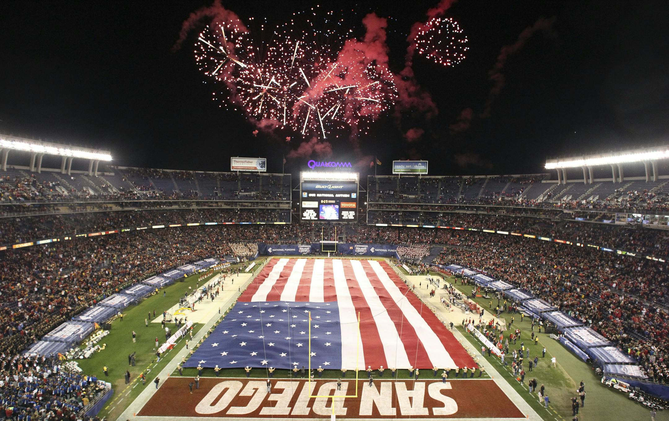 Fireworks explode as the national anthem plays while Marines hold a large U.S. flag during the opening ceremony for the National Funding Holiday Bowl between USC and Wisconsin at Qualcomm Stadium in San Diego on Wednesday, Dec. 30, 2015. (Hayne Palmour IV/San Diego Union-Tribune/TNS) ORG XMIT: 1178754