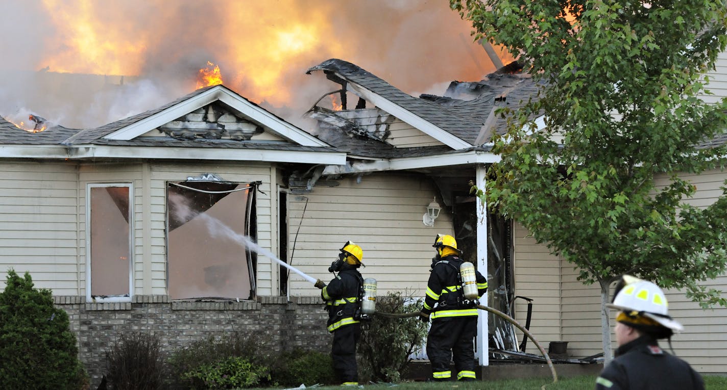 Firefighters from area departments battle the flames after a small plane crashed into a home at 731 Garden Place in Sauk Raids, Minn., Friday, June 20, 2014. (AP Photo/St. Cloud Times, Jason Wachter)