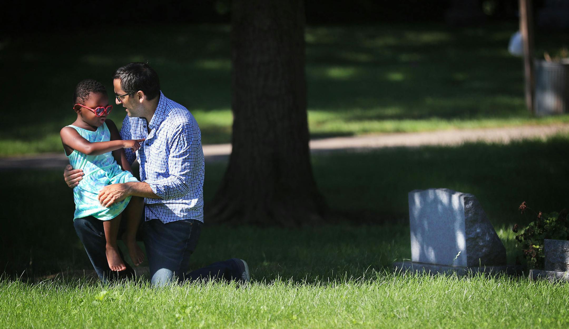 During a visit to Emily Hofher's grave site, Hofher's husband Rob Raub and their daughter Ruby Raub, 4, share a quiet moment together in July in Minneapolis.