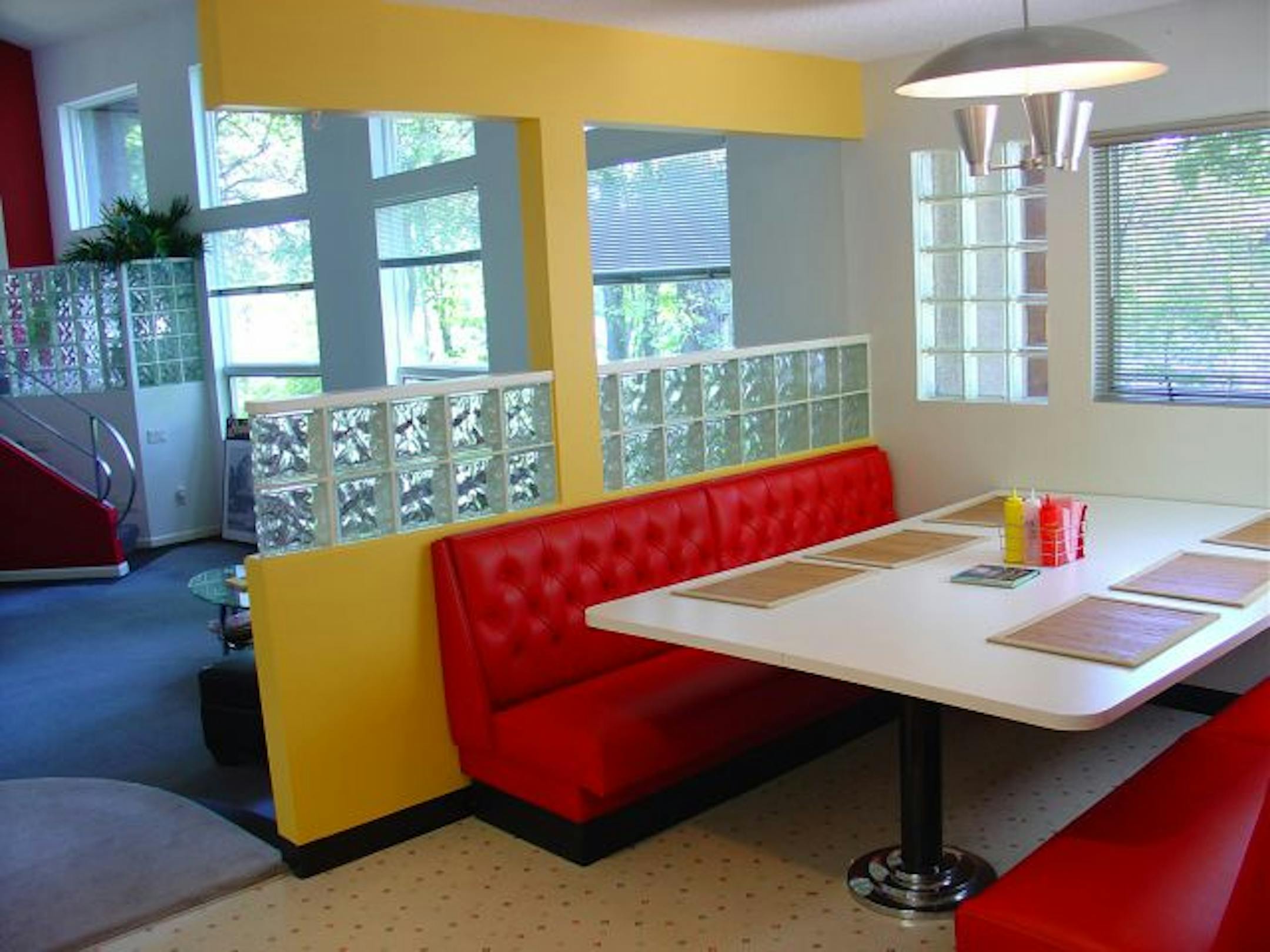 A vintage booth and glass blocks in the dining area; the retro-inspired kitchen has a 1950s Chambers stove and soda fountain stools.