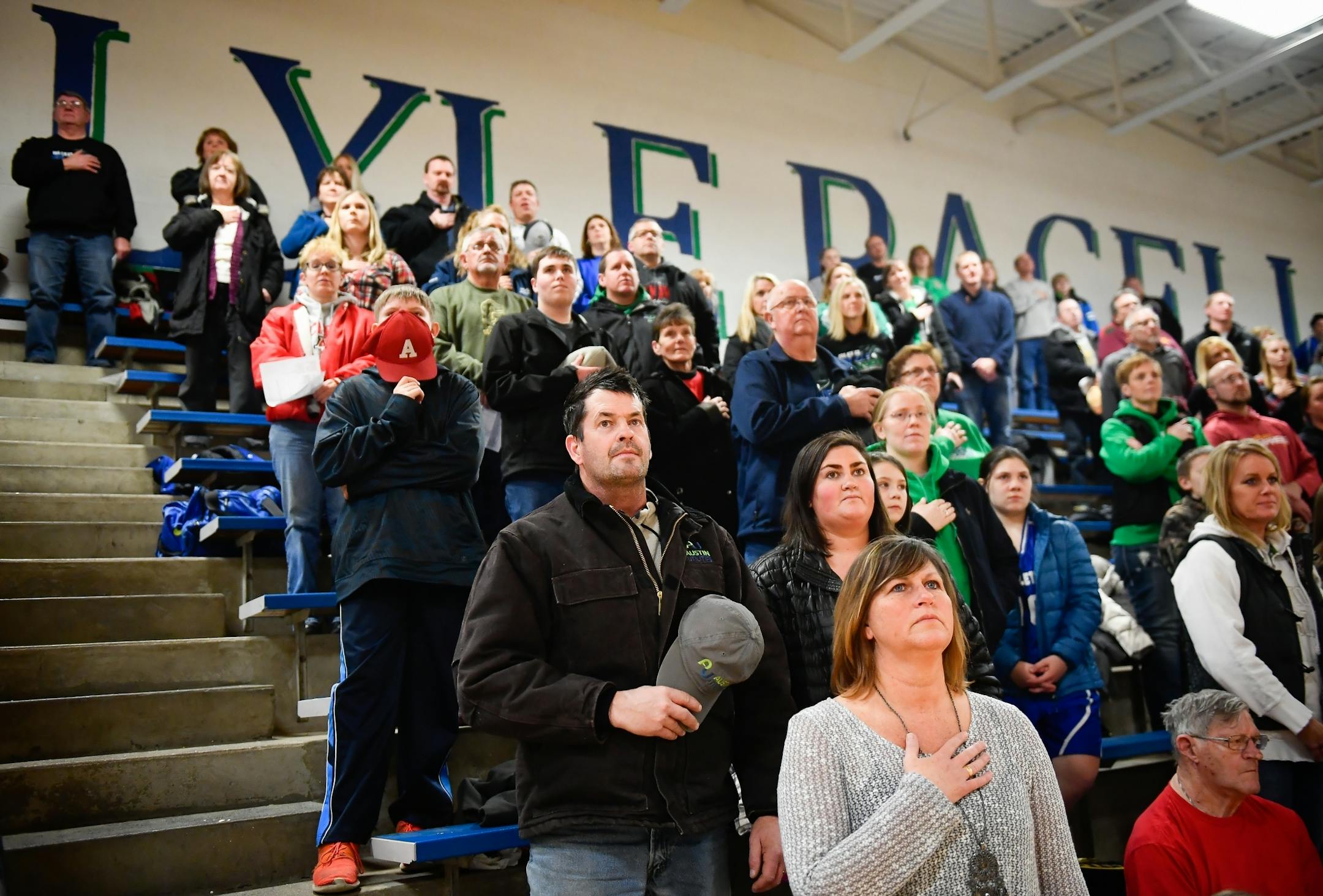 Joe Bartholomew, center, of Lyle, held his hat up to his heart during the playing of the National Anthem Friday night before the start of a high school basketball game at Lyle High School. Bartholomew, a union utility worker, voted for Clinton in the last presidential election.
