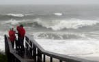 People watch the waves in a rainstorm at Atlantic Ocean at Carolina Beach, N. C., Friday, Oct. 2, 2015. Millions along the East Coast breathed a littl