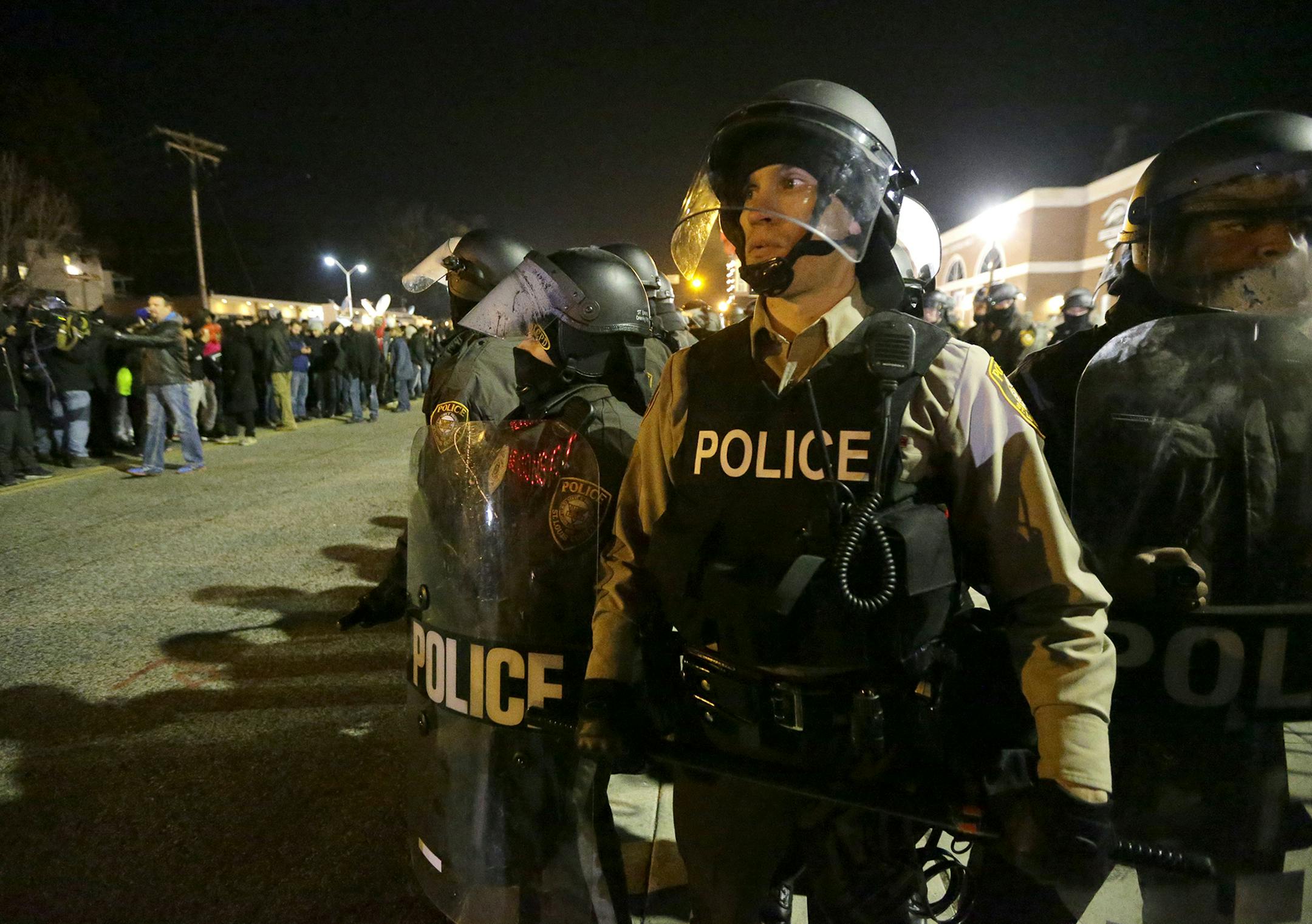 Police watch the street as protesters gather Tuesday, Nov. 25, 2014, in Ferguson, Mo. Missouri's governor ordered hundreds more state militia into Ferguson on Tuesday, after a night of protests and rioting over a grand jury's decision not to indict police officer Darren Wilson in the fatal shooting of Michael Brown, a case that has inflamed racial tensions in the U.S. (AP Photo/Charlie Riedel) ORG XMIT: MIN2014112618050569
