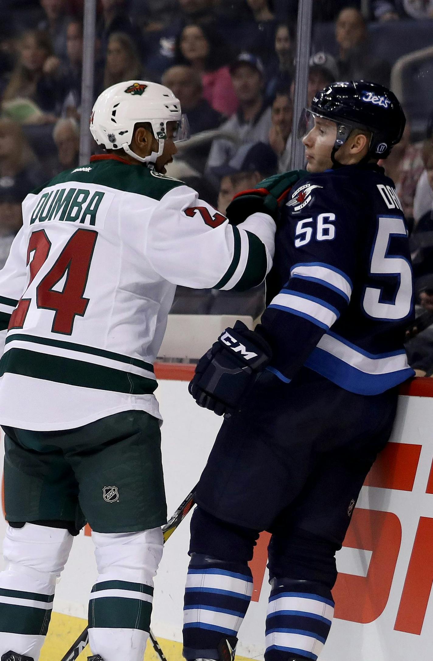 Minnesota Wild's Matt Dumba (24) pushes Winnipeg Jets' Marko Dano (56) against the boards after Dano collided with Wild goaltender Darcy Kuemper (35) during second-period preseason NHL hockey game action against the Winnipeg Jets in Winnipeg, Manitoba, Thursday, Sept. 29, 2016. (Trevor Hagan/The Canadian Press via AP)