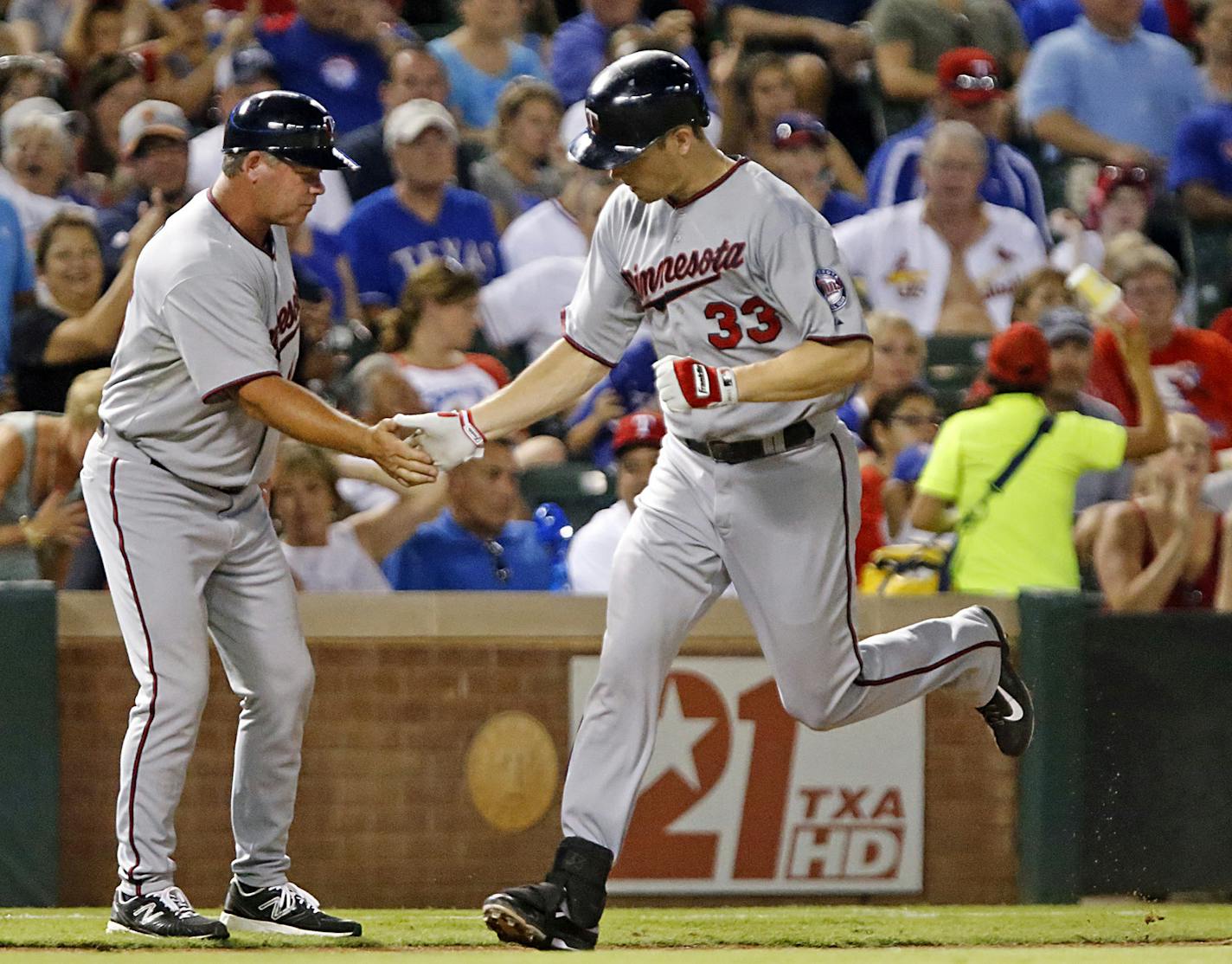 Minnesota Twins first baseman Justin Morneau (33) is congratulated by third base coach Joe Vavra (46) as he rounds third base after hitting the go ahead home run off of Yu Darvish in the seventh inning against the Texas Rangers at The Ballpark in Arlington on Friday night, August 30, 2013. The Twins held on to win the contest 3-2. (Stewart F. House/Special Contributor)