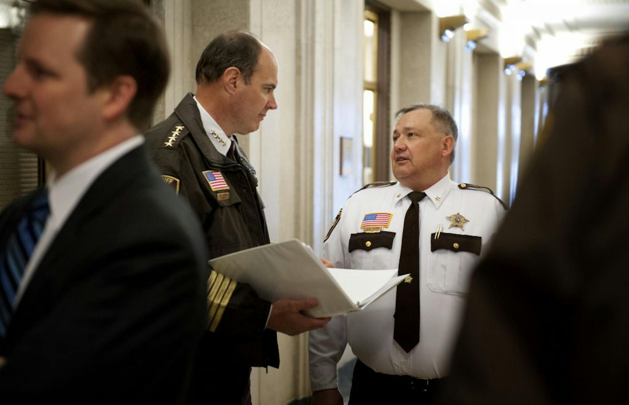 Hennepin County Sheriff Rich Stanek, left background, and Carver County Sheriff Jim Olson talked in a hallway before laying out concerns about gun background checks and mental health issues.