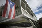 A Puerto Rican flag hangs from the porch of a home that collapsed on top of parked cars after an earthquake hit Guanica, Puerto Rico, Monday, Jan. 6, 