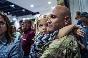 Corrina Eslinger,5, held on tight to her father, Charles, who is a major as they filed in to join a dinner for the soldiers and their families.