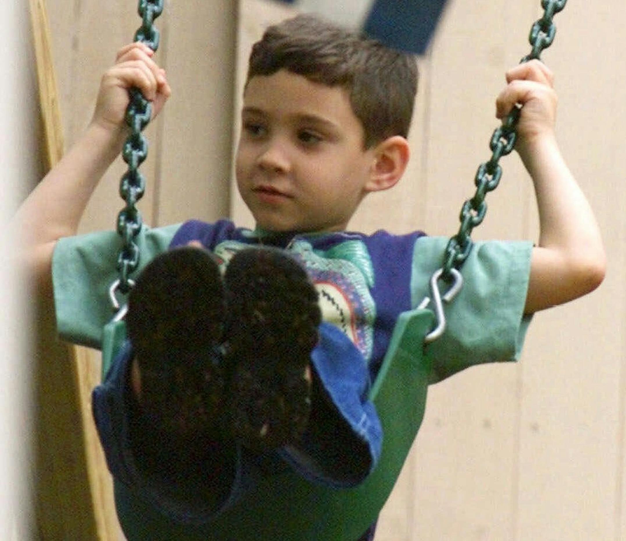 FILE-- Elian Gonzalez swings as a Cuban flag hangs in the foreground, in the backyard of his Miami home in this Friday, April 14, 2000 file photo. Barring a court ruling, Elian would be free to leave U.S. soil for Cuba by 4 p.m. EDT Wednesday, June 28, 2000. Tentative plans were being made for a nighttime arrival in Havana aboard a chartered flight from Washington Dulles International Airport. (AP Photo/Tony Gutierrez)