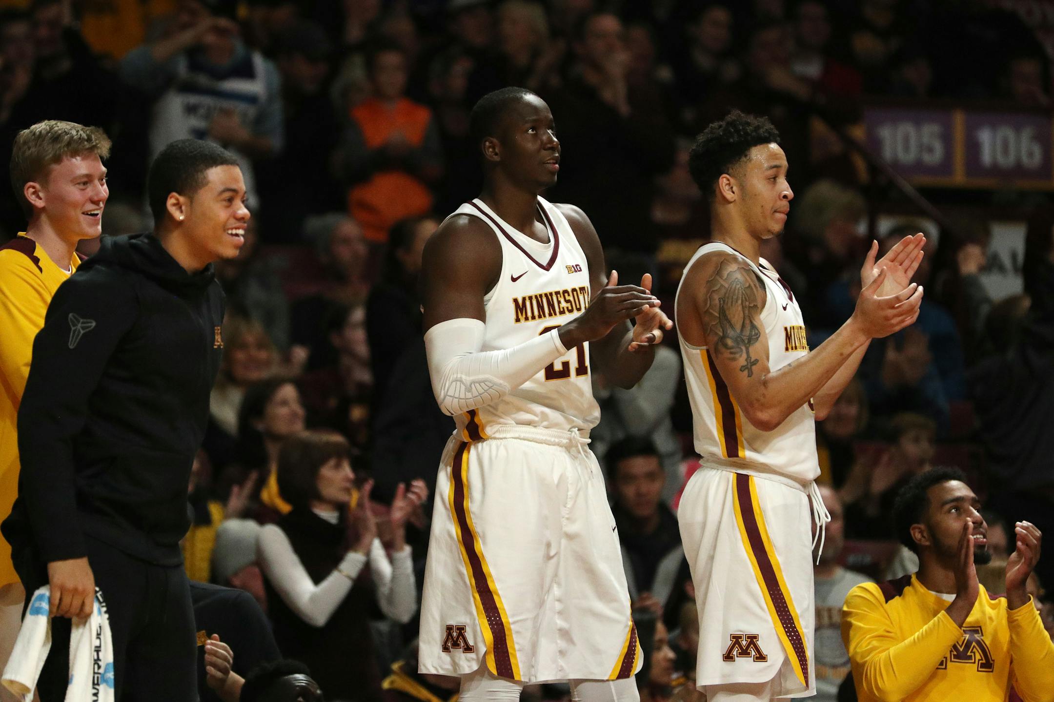 Minnesota Golden Gophers center Bakary Konate (21) and Minnesota Golden Gophers guard Amir Coffey (5) clapped along with their teammates as they watched from the bench in the second half against Harvard.