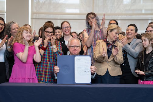 Gov. Tim Walz displays the "trans refuge" bill after he signed it into law on Thursday morning in St. Paul. It was the first of three progressive priorities of the session: a ban on conversion therapy for minors and vulnerable adults and two bills that would make Minnesota a refuge for people traveling here for abortion and gender affirming care.