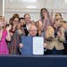 Gov. Tim Walz displays the "trans refuge" bill after he signed it into law on Thursday morning in St. Paul. It was the first of three progressive prio