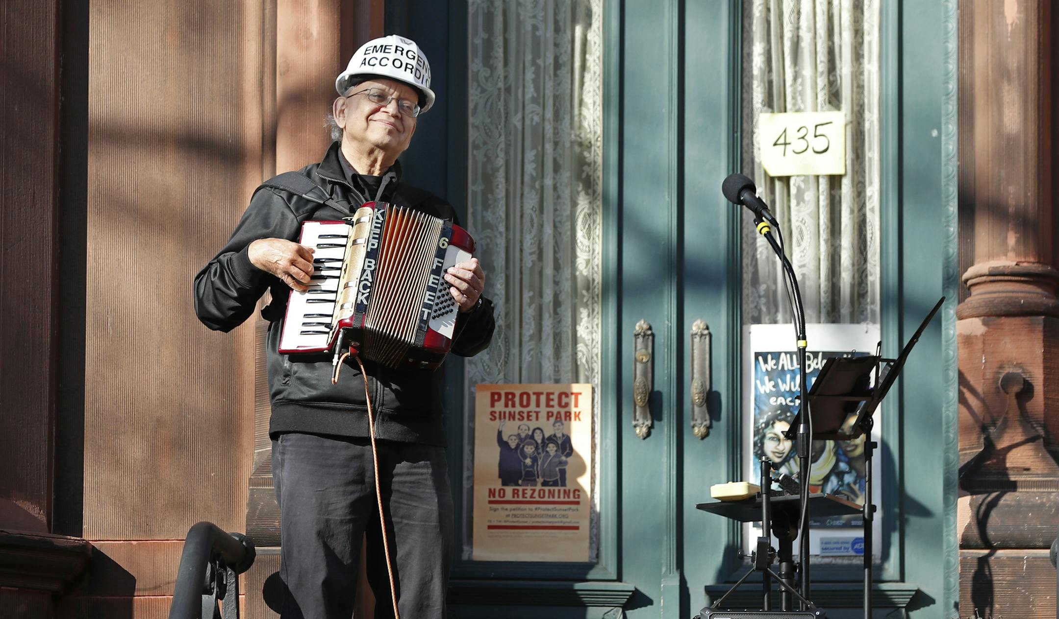 In this Wednesday, April 15, 2020 photo, musician Paul Stein, who has played the accordion since he was eight, entertains neighbors with an "Emergency Accordion Stoop Extravaganza" (EASE) concert from the top step of his stoop in the Sunset Park neighborhood of Brooklyn in New York. "Music…lifts people's spirits and brings them together," Stein says. "We need to keep our spirits up. We need hope now. That's what we need to get through this difficult period." (AP Photo/Kathy Willens)