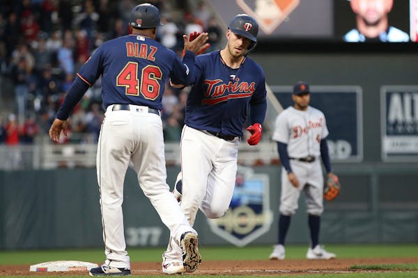 The Twins' Mitch Garver high-fives third base coach Tony Diaz after he hit a home run against the Tigers during the fourth inning