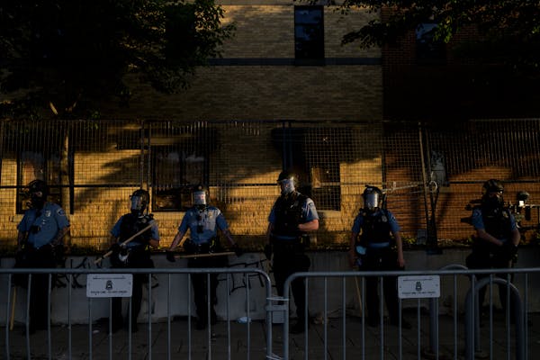 Minneapolis Police officers stood by as protesters demonstrated outside the third precinct. ]