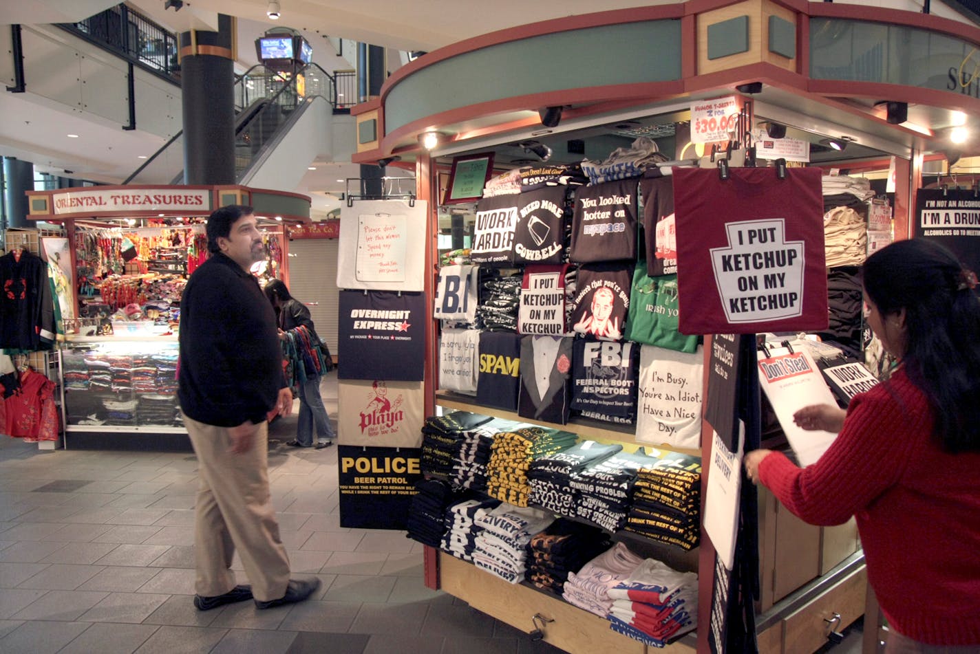 Ramesh Wahi, left, was among the original cart merchants when the Mall of America opened in 1992. Here he arranges T-shirts with his niece, Jyoti Sharma.