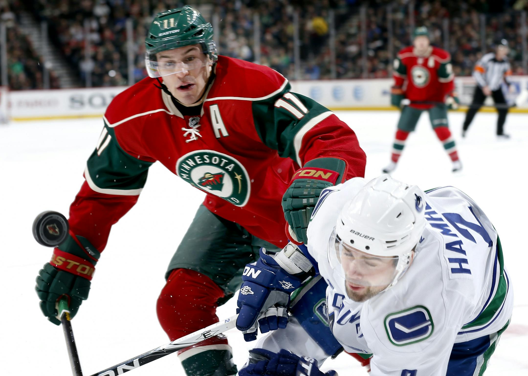 Minnesota Wilds' Zach Parise (11) and Vancouver Canucks' Dan Hamhuis (2) fought for the puck in the first period.