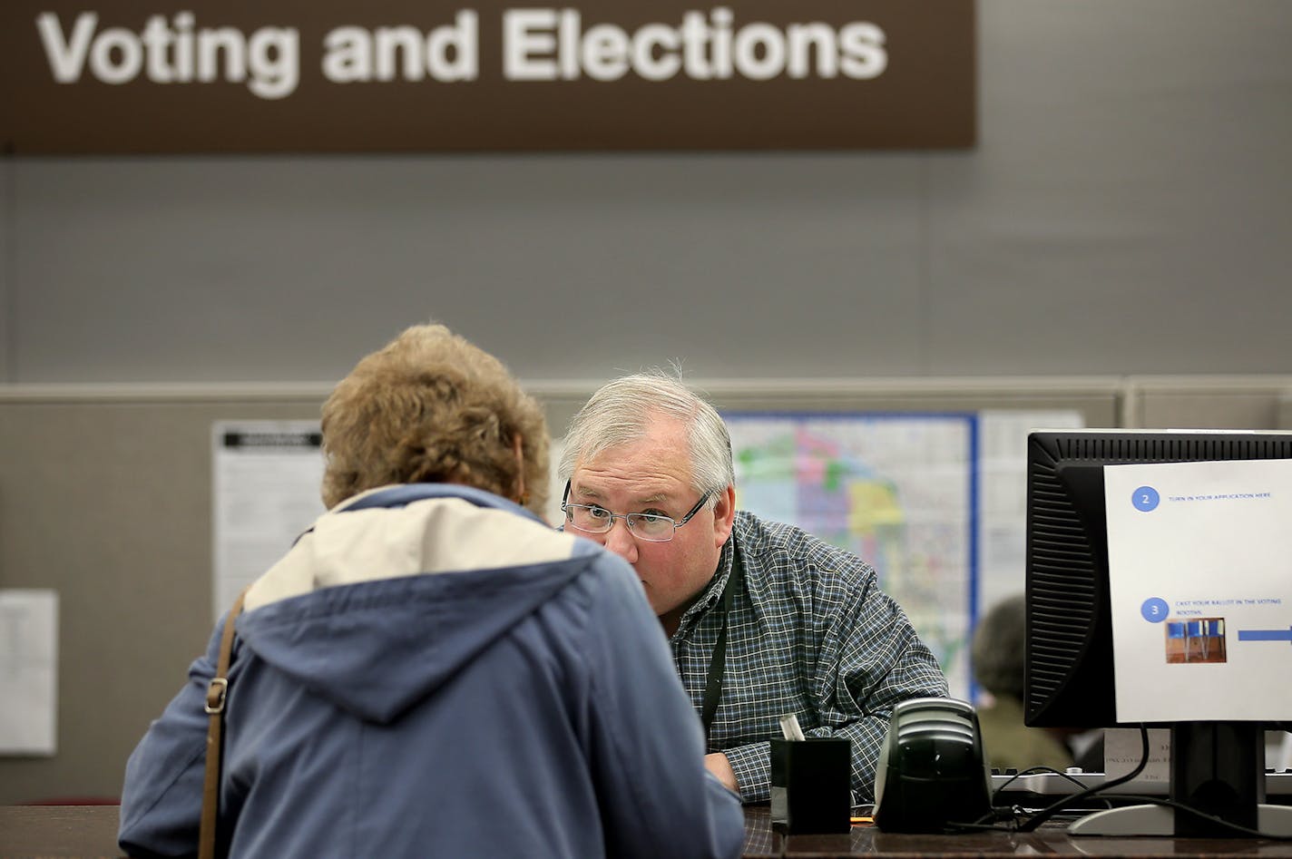 Hennepin County Voting and Elections Office Specialist Andrew Krueger helped voter Mary Ellen Gallick with her ballot at the absentee-voting polls at the Hennepin County Government Center, Thursday, October 23, 2014 in Minneapolis, MN. ] (ELIZABETH FLORES/STAR TRIBUNE) ELIZABETH FLORES &#x2022; eflores@startribune.com