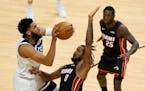 Timberwolves center Karl-Anthony Towns, left, goes up for a shot against Miami forward Trevor Ariza (8) as guard Kendrick Nunn (25) looks on during th
