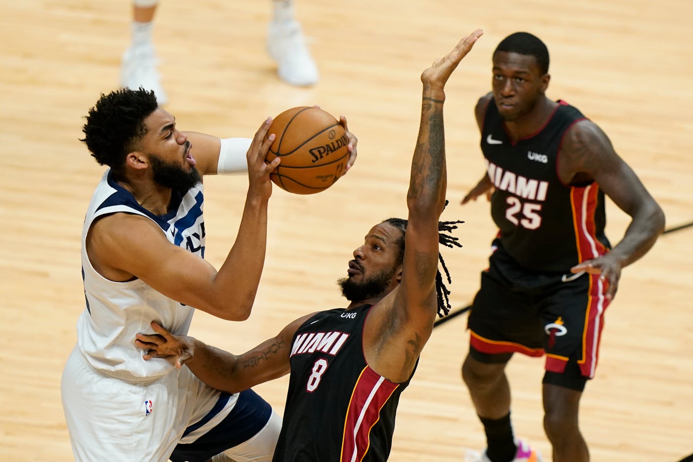 Timberwolves center Karl-Anthony Towns, left, goes up for a shot against Miami forward Trevor Ariza (8) as guard Kendrick Nunn (25) looks on during the first half