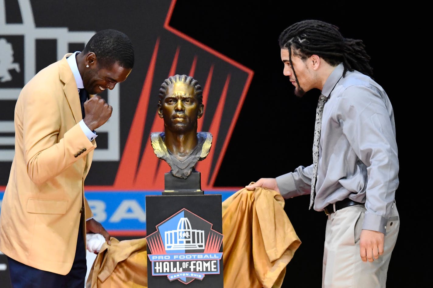 Former NFL wide receiver Randy Moss, left, unveils his bust with his presenter, son Thaddeus Moss, during inductions at the Pro Football Hall of Fame on Saturday, Aug. 4, 2018, in Canton, Ohio. (AP Photo/David Richard)