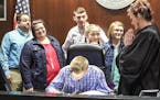 Eric and Phyllis Watson of Gardner (left) watch as newly adopted son Cody, 15, signs documents during an adoption hearing on Monday, March 12, 2018 in