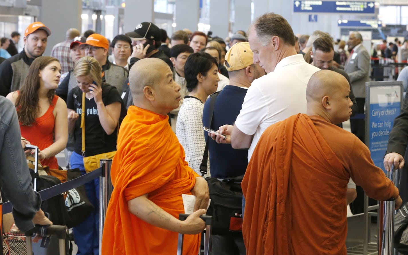 Chris Alguire, from Dallas, Texas, white shirt, makes a business call as he stands in an American Airlines ticketing line with other passengers at O'Hare International Airport Tuesday, May 13, 2014, in Chicago. Smoke in a regional radar facility forced a halt to all incoming and outgoing flights at both of Chicago's airports.