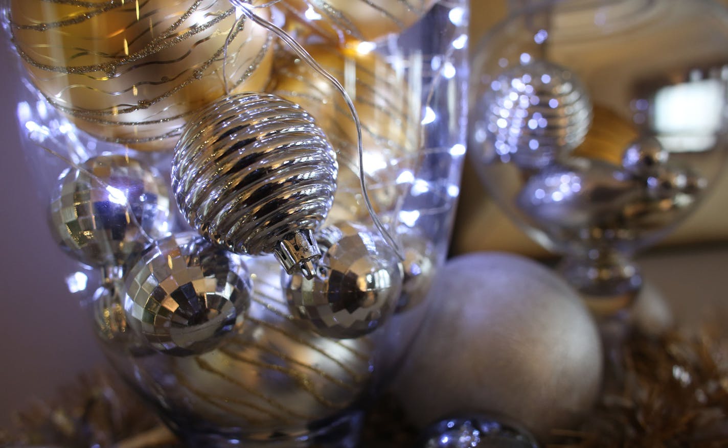 Apothecary jars are filled with silver and gold balls in different textures and finishes, illuminated by battery-powered lights.