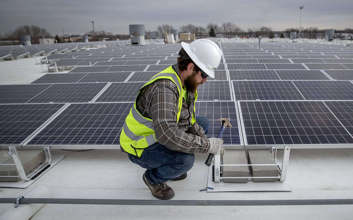 Reed Martin of Cedar Creek Energy installed solar panels on the roof of Brin Glass on Monday in Fridley.