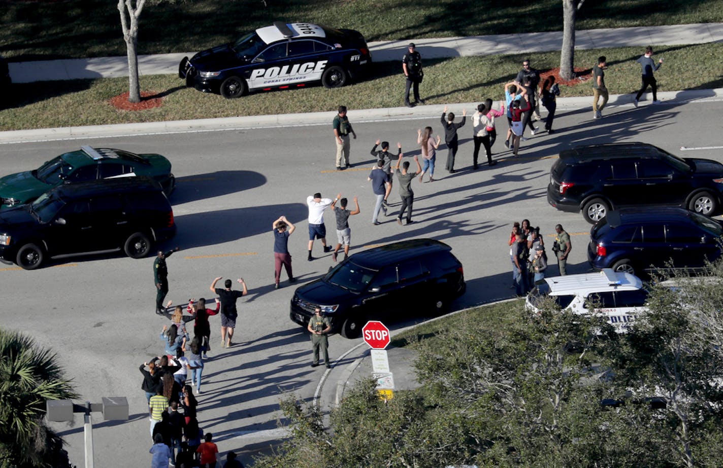 Students held their hands in the air as they were evacuated by police from Marjory Stoneman Douglas High School in Parkland, Fla., after a shooter opened fire on the campus Feb. 14, 2018.