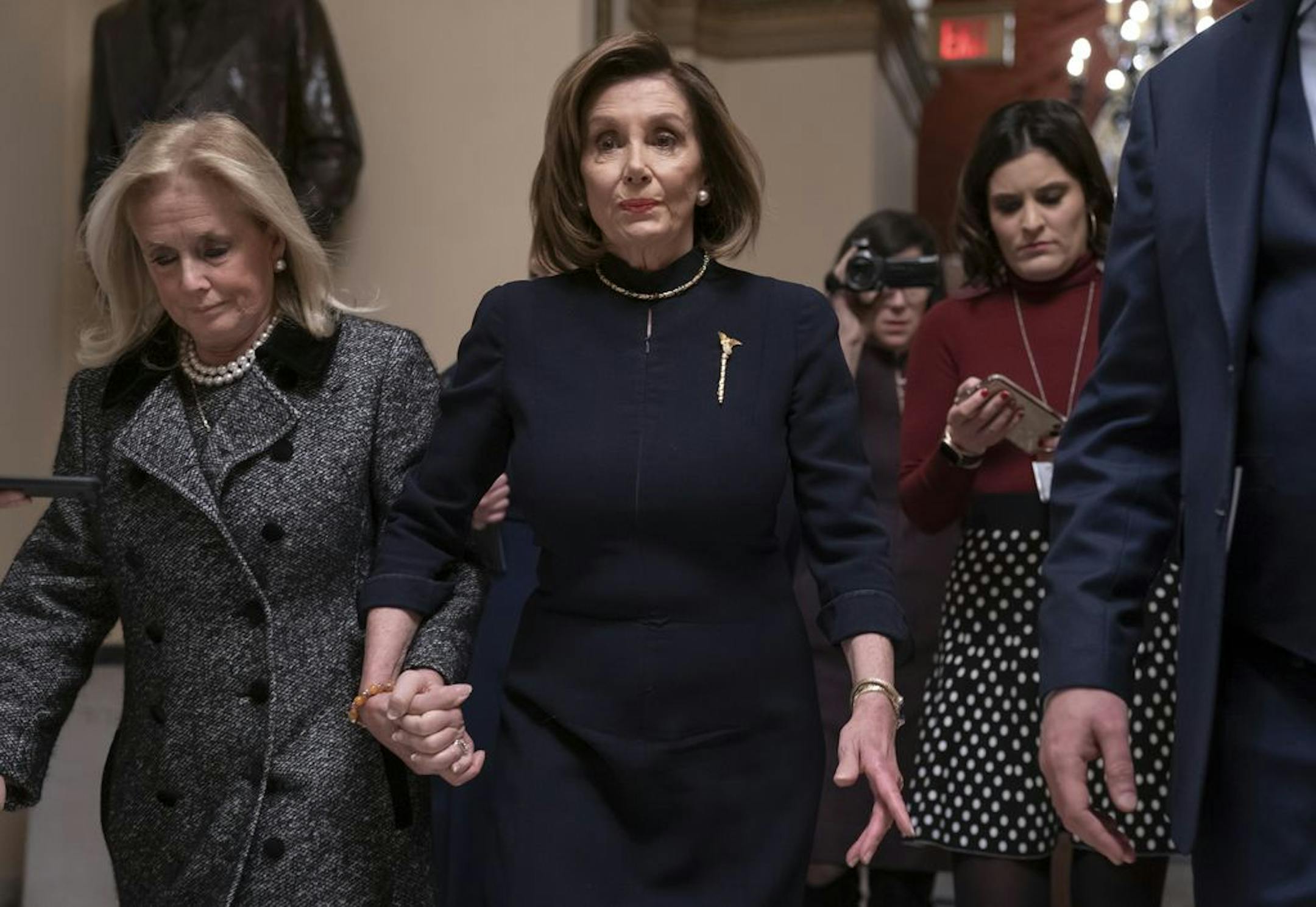 Speaker of the House Nancy Pelosi, D-Calif., holds hands with Rep. Debbie Dingell, D-Mich., as they walk to the chamber where the Democratic-controlled House of Representatives begins a day of debate on the impeachments charges against President Donald Trump for abuse of power and obstruction of Congress, at the Capitol in Washington, Wednesday, Dec. 18, 2019.