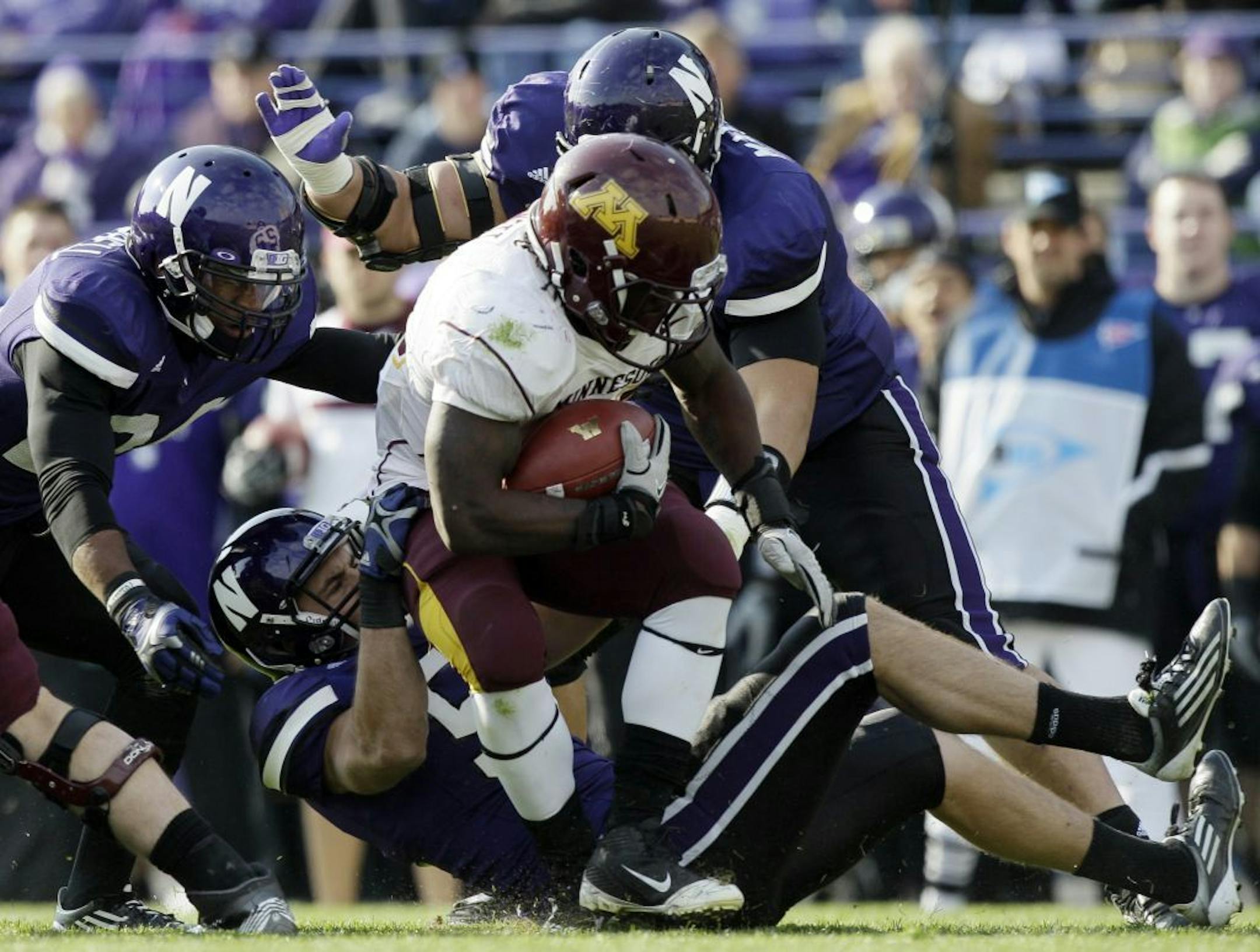Minnesota running back Duane Bennett (22) is tackled by Northwestern linebacker Bryce McNaul (51), defensive back Ibraheim Campbell (24) and defensive line Niko Mafuli( 93) in the first half of an NCAA college football game, Saturday, Nov. 19, 2011, in Evanston, Ill.