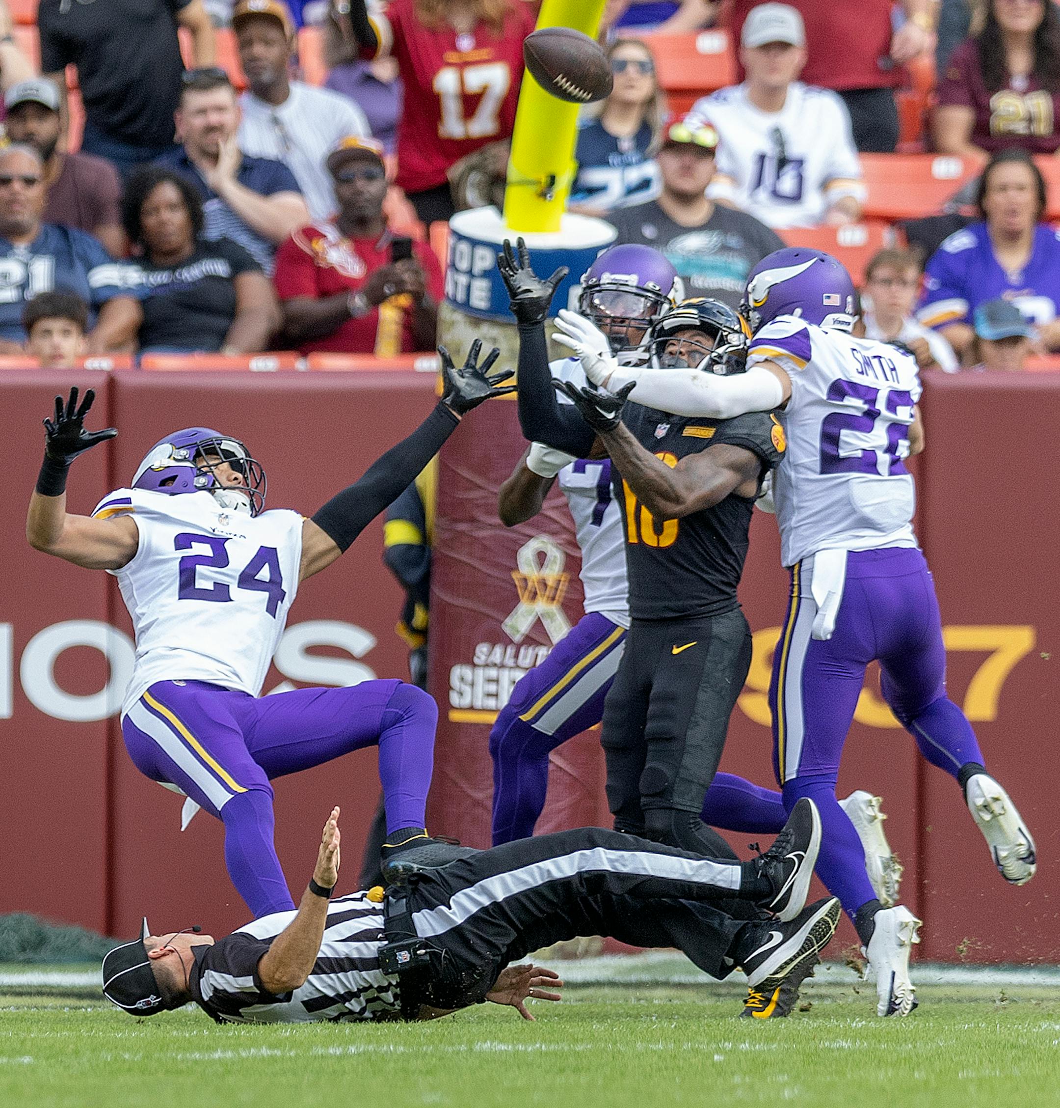 Washington Commanders wide receiver Curtis Samuel (10) comes down with a catch as Minnesota Vikings safety Camryn Bynum (24) trips over the referee in the third quarter.