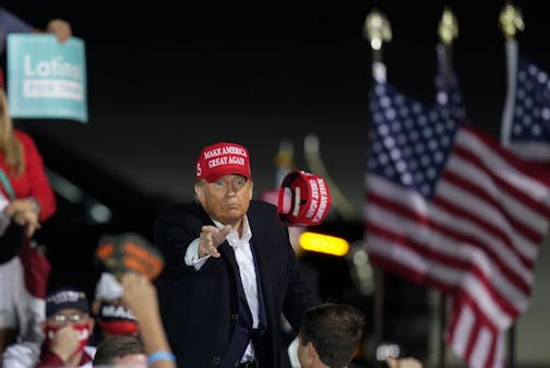 President Donald Trump throws a hat to a supporter during a campaign rally at Des Moines International Airport, Wednesday, Oct. 14, 2020, in Des Moines, Iowa.